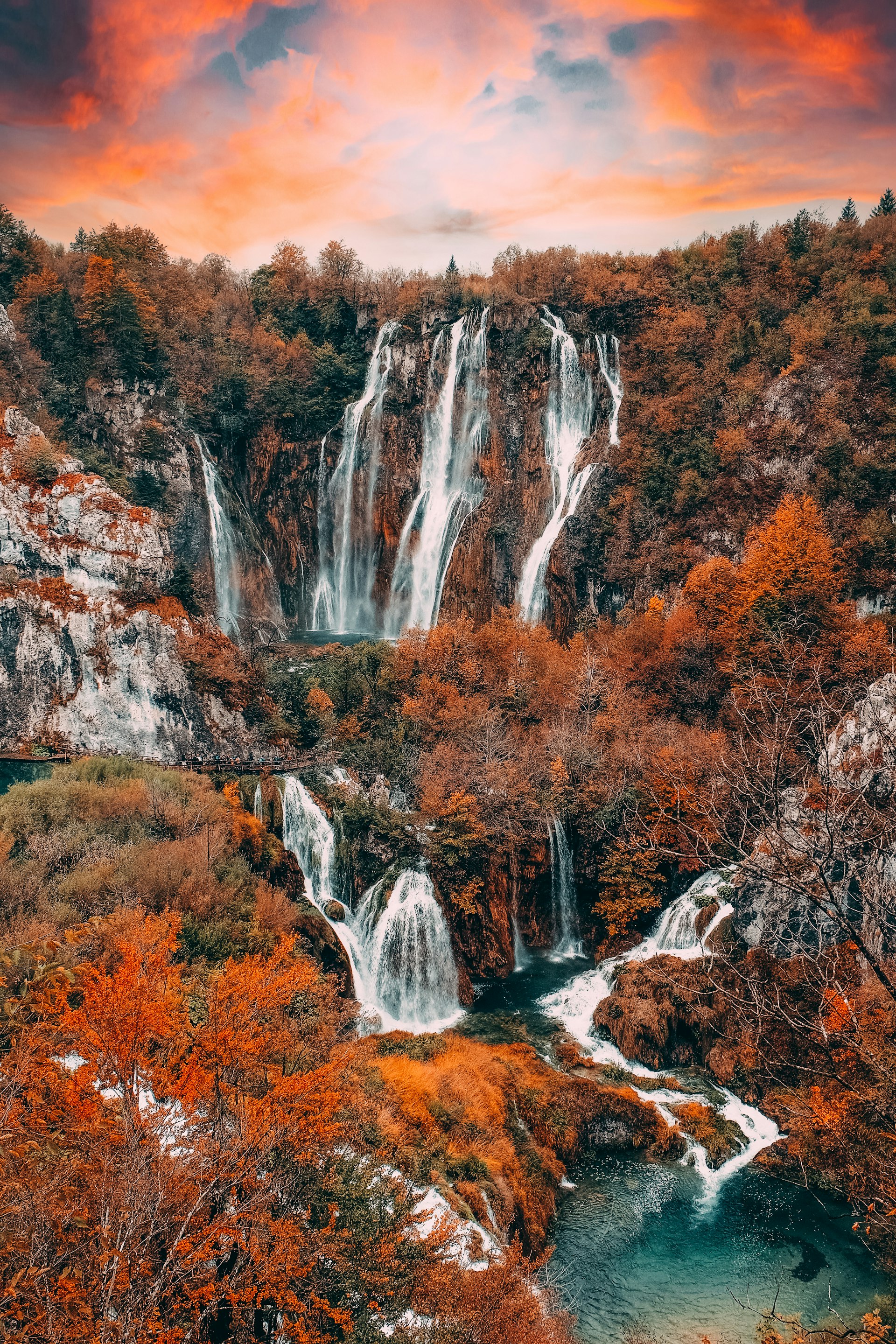 Cascading waterfalls through forest at Plitvice Lakes during autumn sunrise