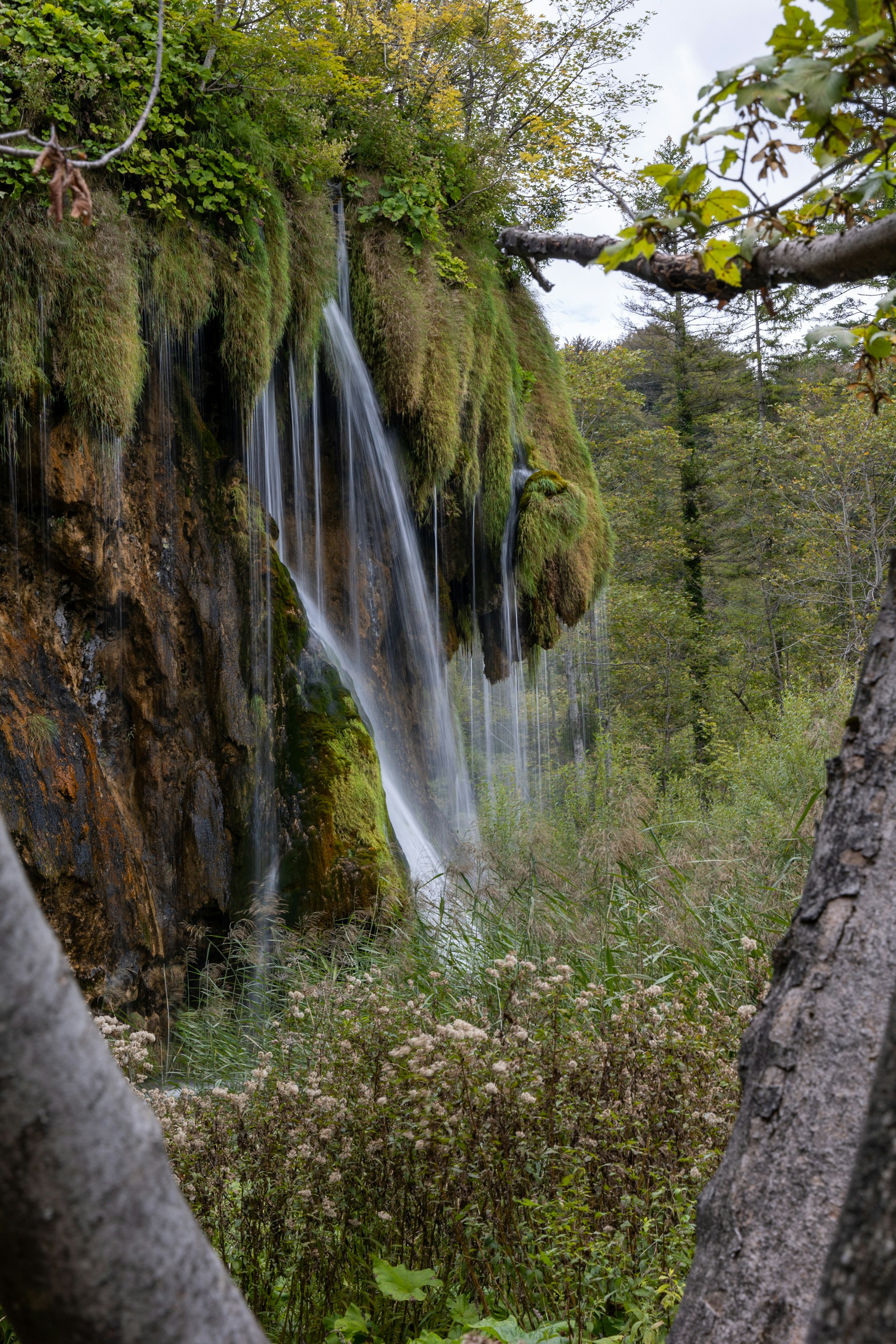 Partially frozen waterfall surrounded by snow and ice formations at Plitvice Lakes